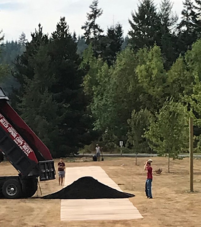 Dump truck leaving first delivery of dirt on cardboard.